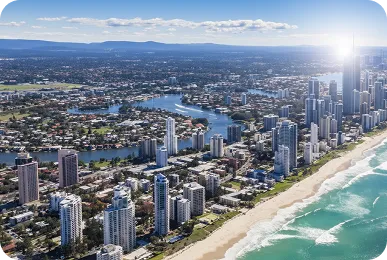 Aerial view of beachfront and skyline, Queensland, featuring high-rise coastal apartments, sandy beaches, and ocean waves.