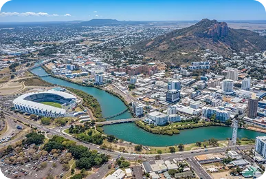 Aerial view of Townsville city, Queensland, featuring Queensland Country Bank Stadium, Ross River, and Castle Hill in the background.